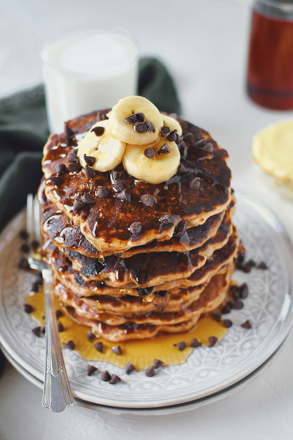 Banana Chocolate Chip Pancakes stacked high, topped with banana slices and extra mini chocolate chips.