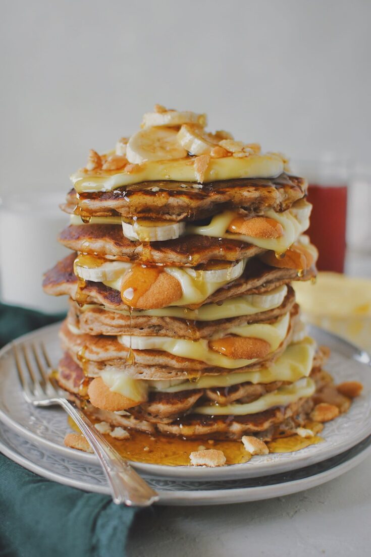 Banana Pudding Pancakes stacked up with pudding layered in between along with bananas and nilla wafers and finished with a drizzle of maple syrup.