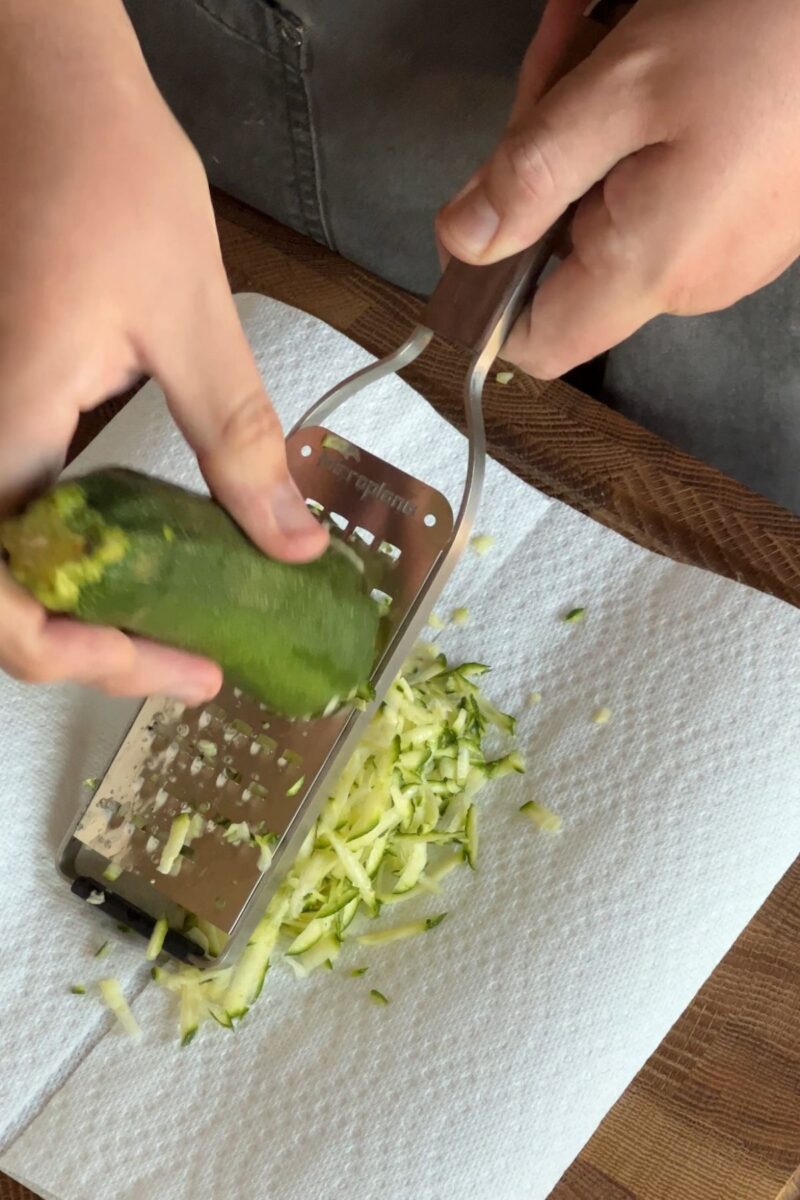 Grating zucchini over a couple of paper towels.
