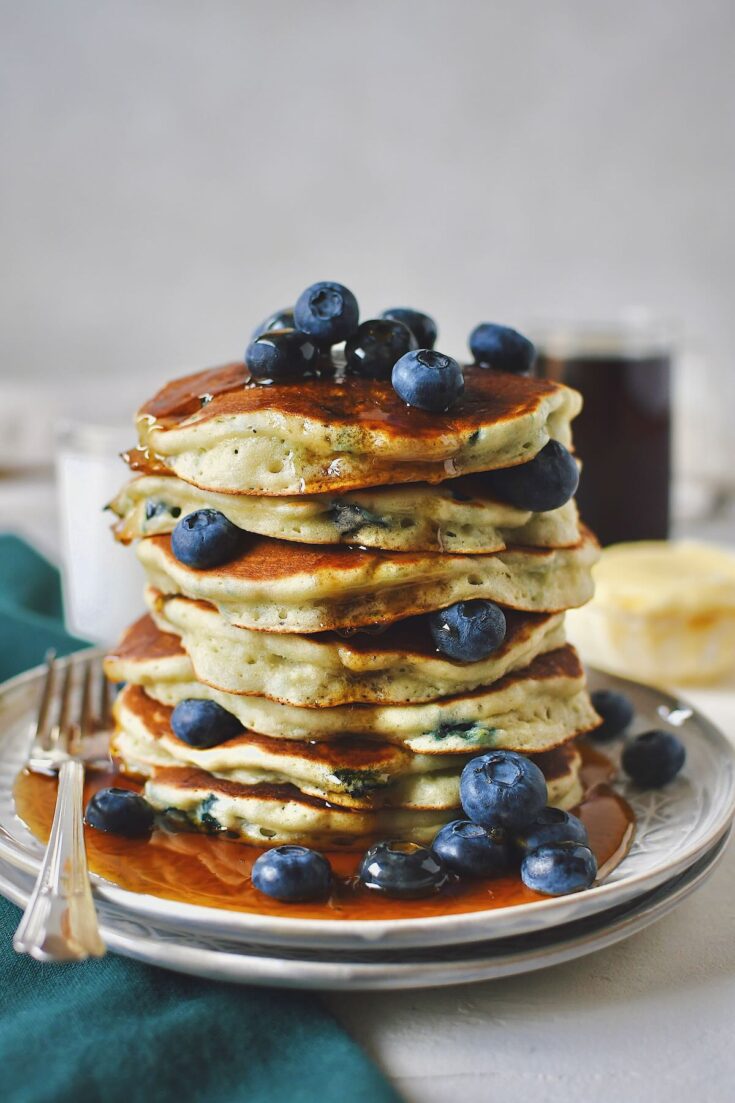 Blueberry Pancakes, stacked high, topped with more fresh blueberries and a generous pour of real maple syrup.