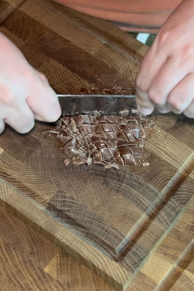 Chopping the chocolate bar on a wood cutting board.
