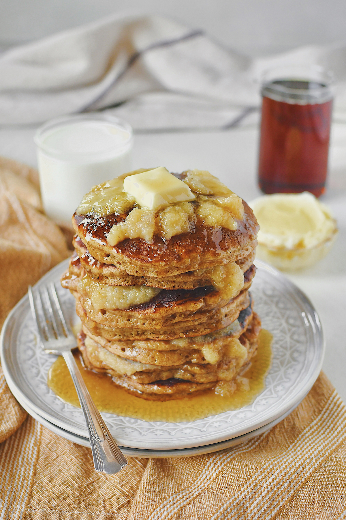 Applesauce Pancakes stacked high, with applesauce in between and on top. Topped with a pat of butter and lots of real maple syrup.