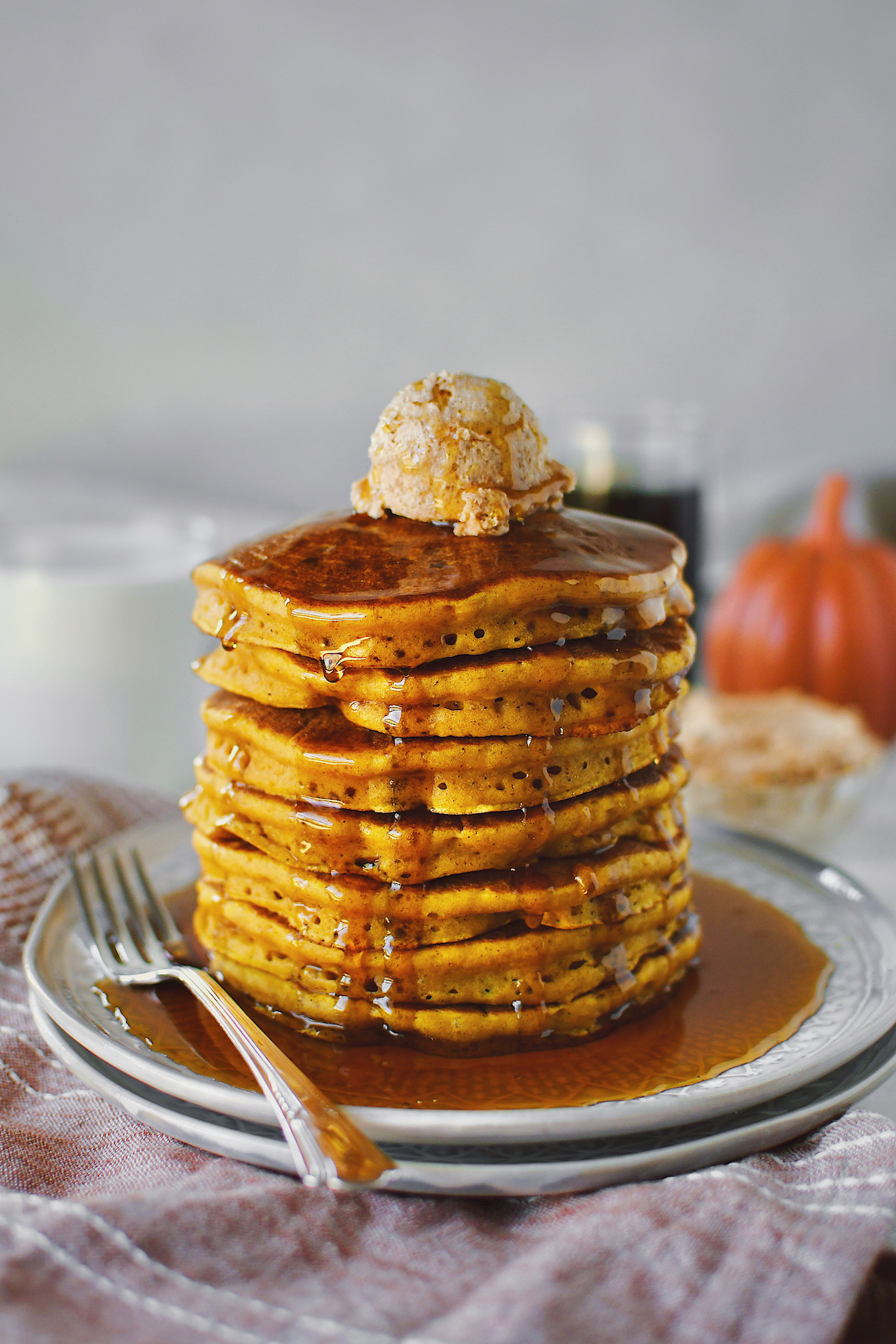 Pumpkin Pancakes stacked 7 high and topped with a large scoop of cinnamon butter and real maple syrup.