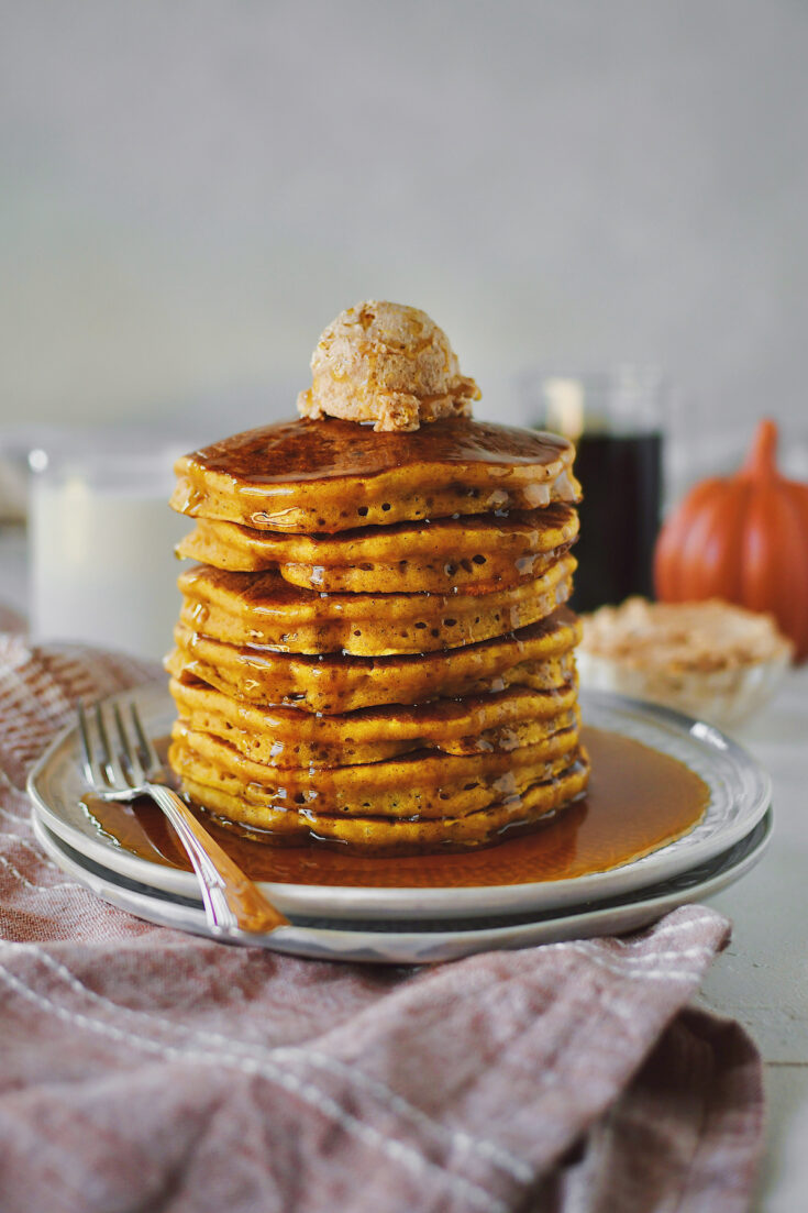 Pumpkin Pancakes stacked 7 high and topped with a large scoop of cinnamon butter and real maple syrup.