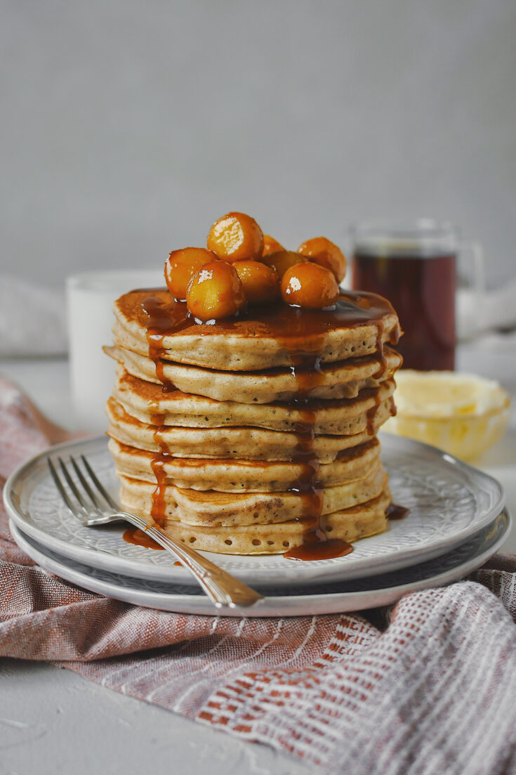 Caramel Apple Pancakes stacked high and topped with mini caramel apples and their sauce.