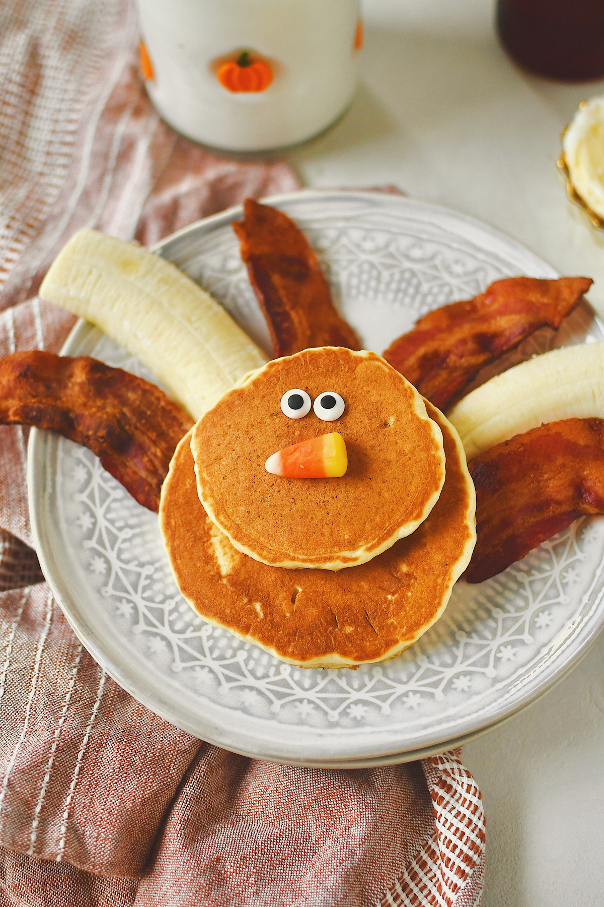 Turkey Pancakes on a plate, with banana and bacon tail feathers, candy corn beak and candy eyes.