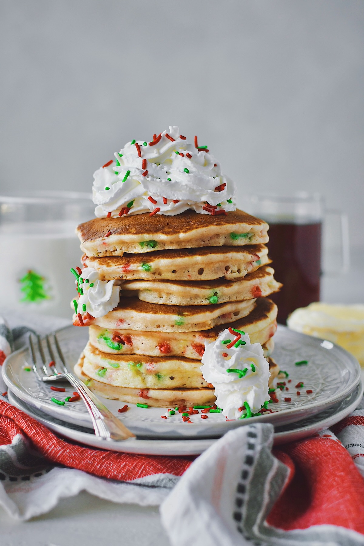 Christmas Pancakes stacked high and topped with spray whipped cream and extra christmas jimmy sprinkles.