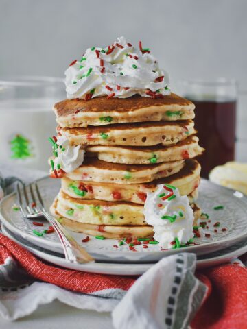 Christmas Pancakes stacked high and topped with spray whipped cream and extra christmas jimmy sprinkles.