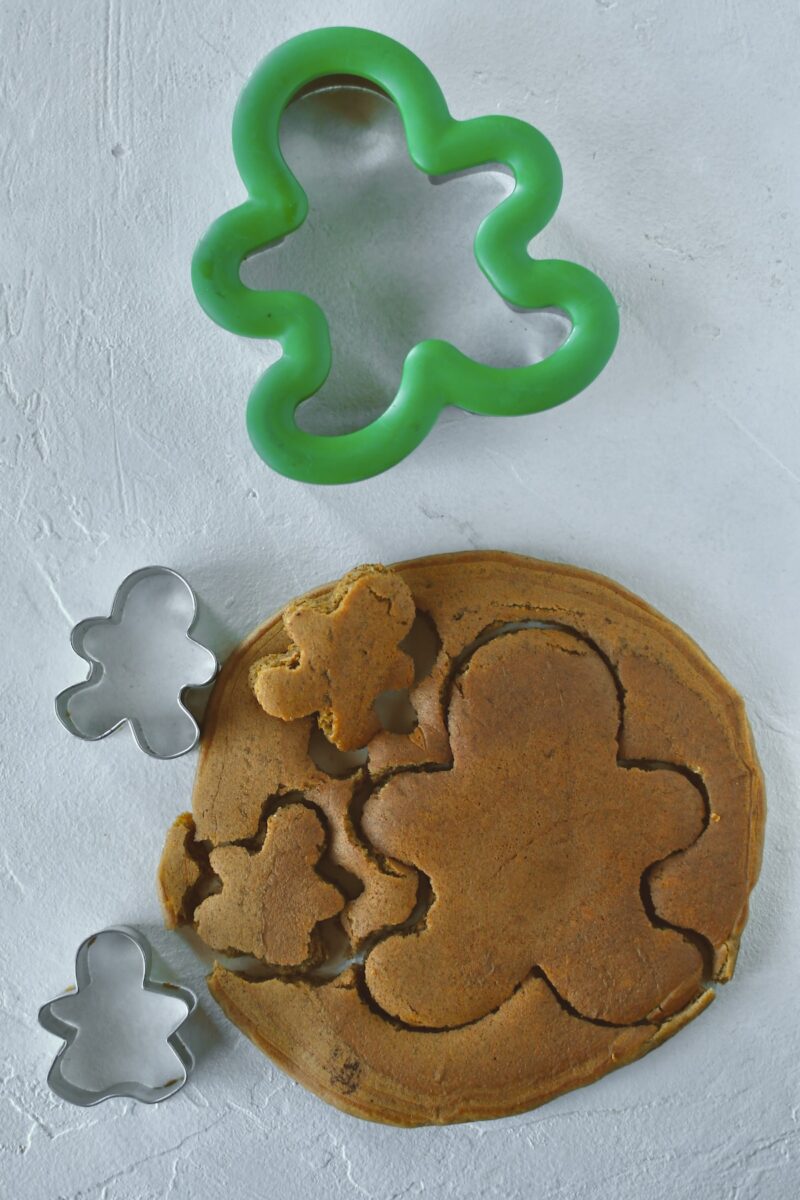 Using cookie cutters to cut gingerbread people out of large gingerbread pancakes.